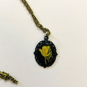 Tiny yellow dried flower in black bezel necklace.